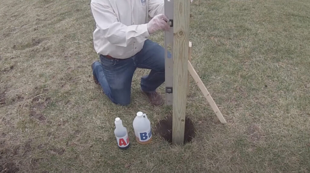 a worker prepares to install a post into the ground using postloc expanding polyurethane foam
